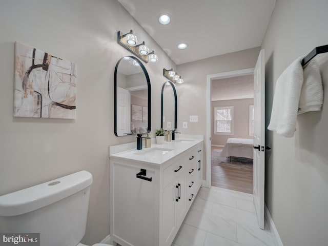 bathroom with toilet, a sink, recessed lighting, double vanity, and baseboards