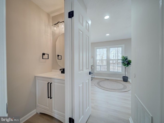 bathroom with vanity, wood finished floors, visible vents, baseboards, and recessed lighting