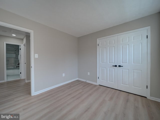 unfurnished bedroom featuring a closet, baseboards, and light wood-style floors