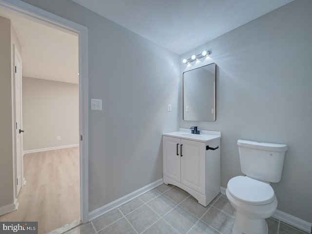 bathroom featuring vanity, toilet, baseboards, and tile patterned flooring