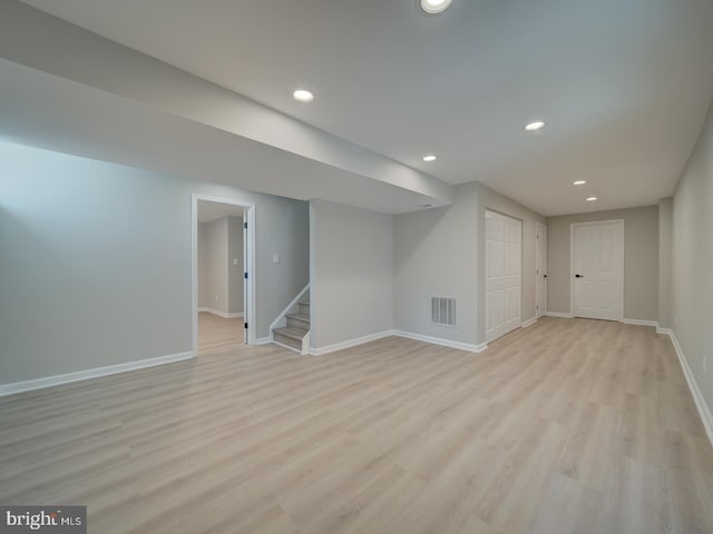 finished basement with visible vents, baseboards, stairway, recessed lighting, and light wood-style flooring