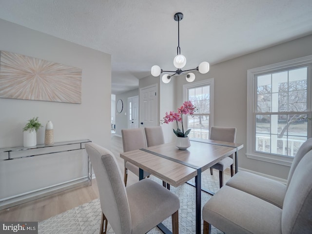 dining room with an inviting chandelier, wood finished floors, and a textured ceiling