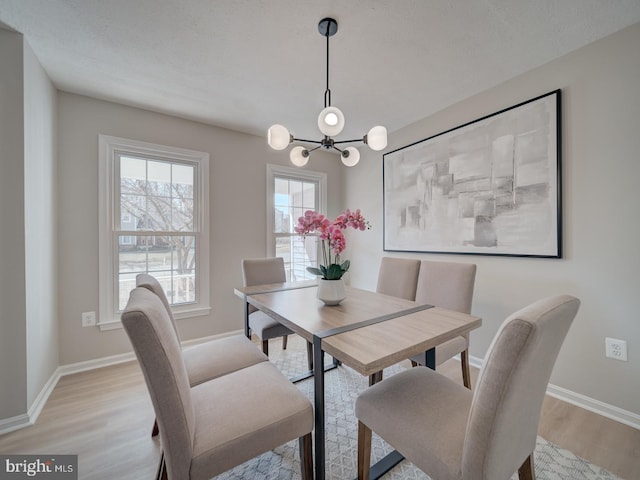 dining room with baseboards, light wood-style floors, and an inviting chandelier