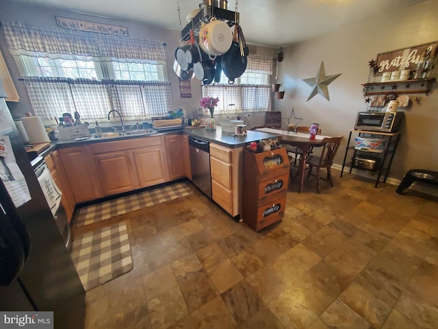 kitchen with stainless steel dishwasher, light brown cabinets, a sink, a peninsula, and baseboards