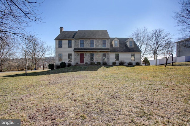 view of front of home featuring a front yard, fence, stone siding, and a chimney