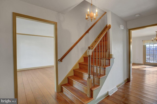 stairway with visible vents, baseboards, an inviting chandelier, and wood-type flooring