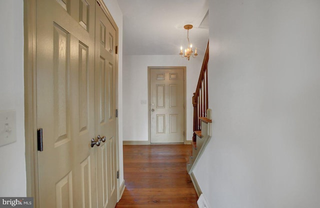 corridor featuring stairs, a notable chandelier, wood finished floors, and baseboards