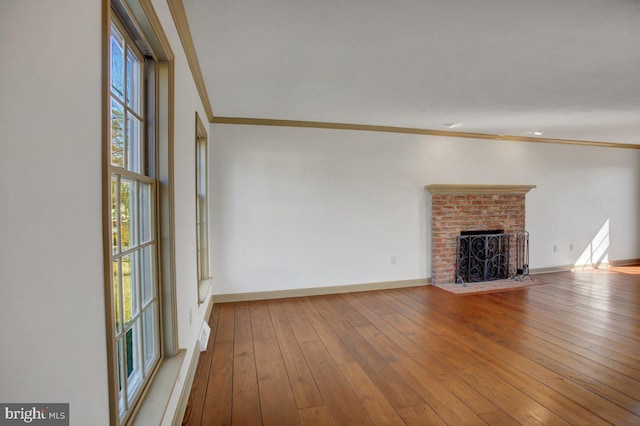 unfurnished living room featuring hardwood / wood-style floors, a brick fireplace, baseboards, and ornamental molding