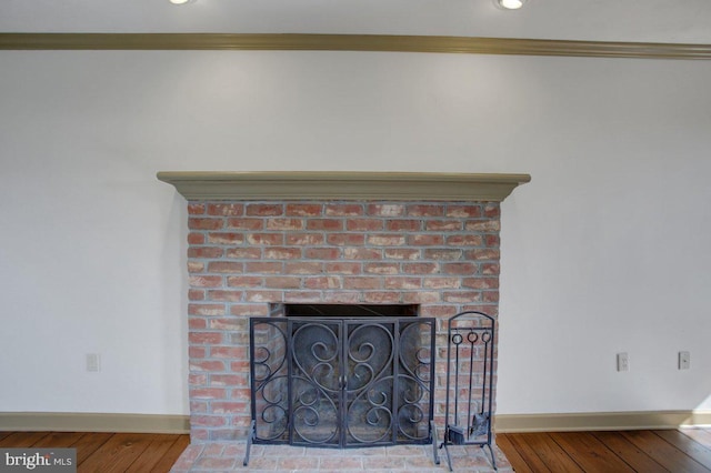 room details featuring baseboards, a brick fireplace, and wood finished floors