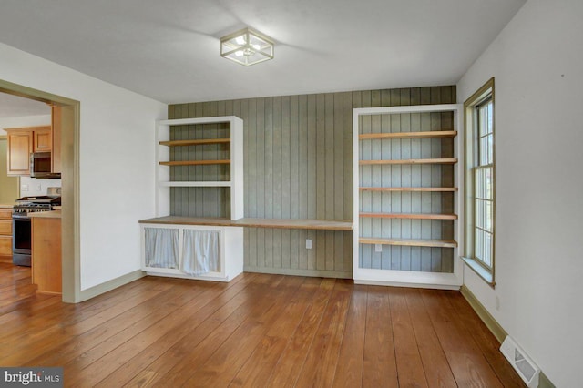 spare room featuring a wealth of natural light, visible vents, wood-type flooring, and baseboards