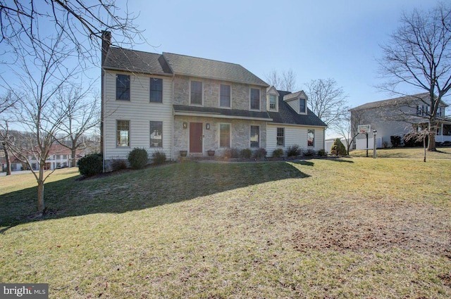 colonial house with stone siding, a chimney, and a front yard