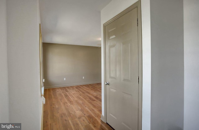 corridor with baseboards and wood finished floors