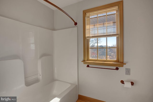 bathroom with shower / bathing tub combination and baseboards