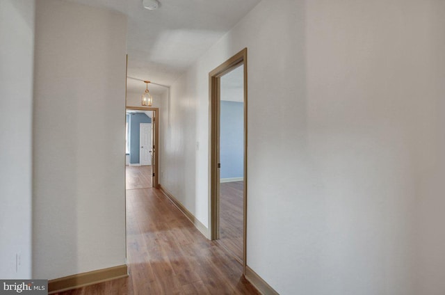 corridor with wood finished floors and baseboards