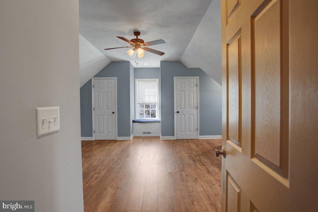 additional living space featuring hardwood / wood-style floors, lofted ceiling, baseboards, and ceiling fan