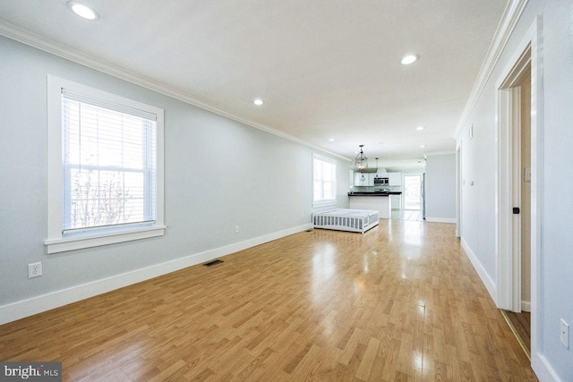 unfurnished living room with crown molding, light wood-style flooring, and baseboards