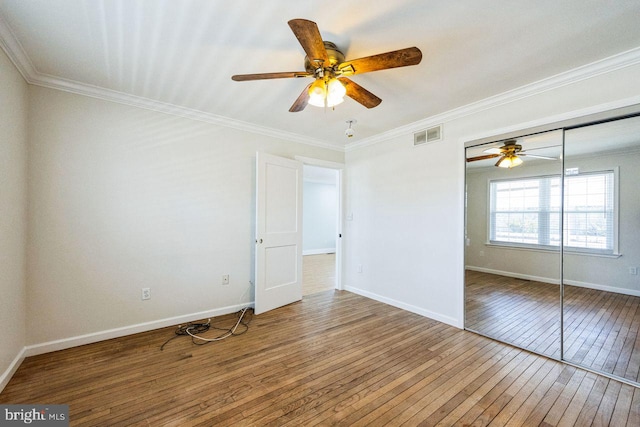 unfurnished bedroom with visible vents, crown molding, baseboards, and hardwood / wood-style flooring