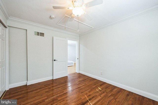 unfurnished bedroom featuring visible vents, baseboards, attic access, ornamental molding, and wood finished floors