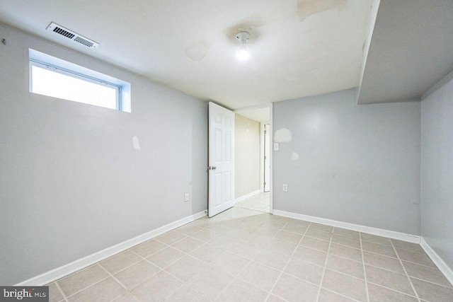 below grade area featuring light tile patterned flooring, visible vents, and baseboards