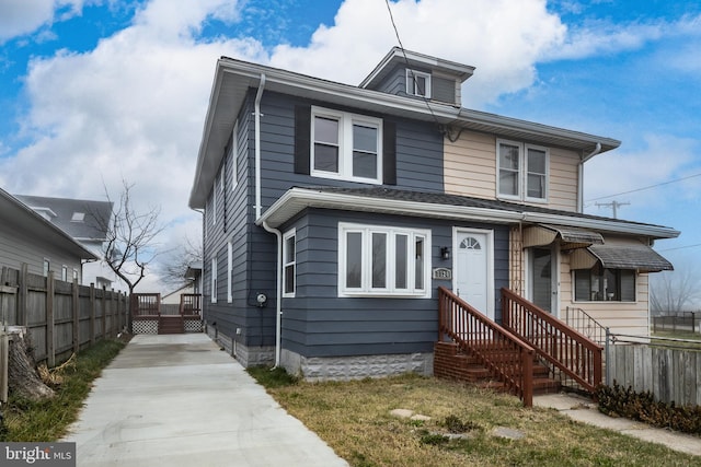 american foursquare style home featuring fence and concrete driveway