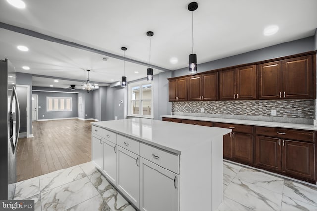 kitchen featuring marble finish floor, stainless steel fridge, light countertops, and decorative backsplash