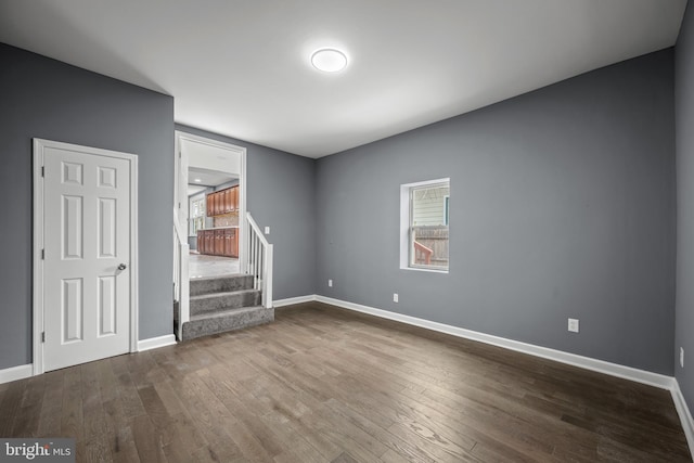 spare room featuring wood-type flooring, stairs, and baseboards