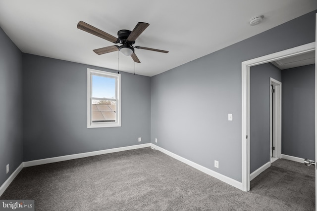 empty room with ceiling fan, dark carpet, and baseboards