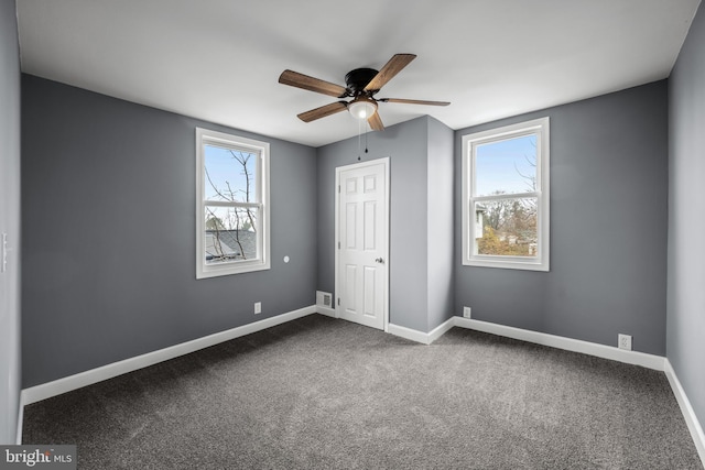 unfurnished bedroom featuring a ceiling fan, dark colored carpet, visible vents, and baseboards