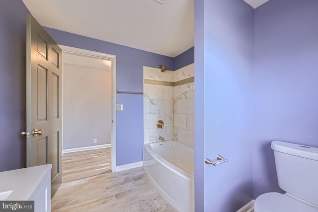 full bathroom featuring toilet, washtub / shower combination, vanity, wood finished floors, and baseboards