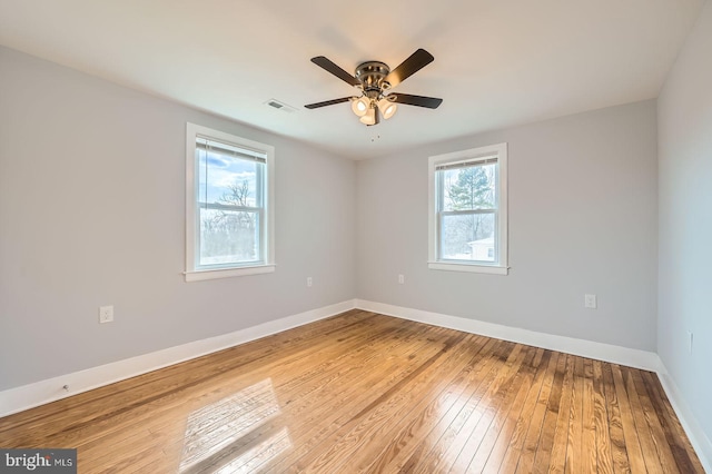 empty room featuring a ceiling fan, wood-type flooring, visible vents, and baseboards