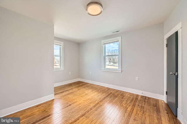 spare room with baseboards, visible vents, and hardwood / wood-style floors