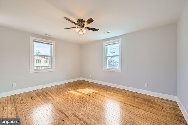 empty room with a wealth of natural light, visible vents, and hardwood / wood-style flooring