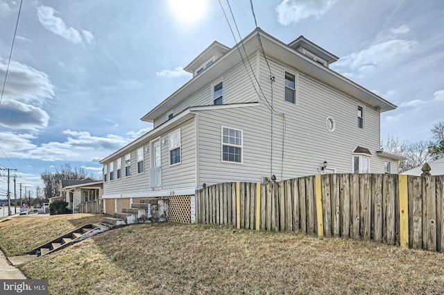 view of side of home with fence and a yard