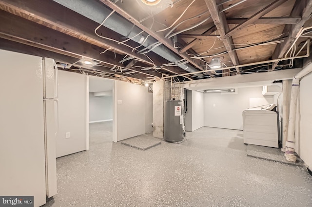 unfinished basement featuring water heater, washer and dryer, and freestanding refrigerator