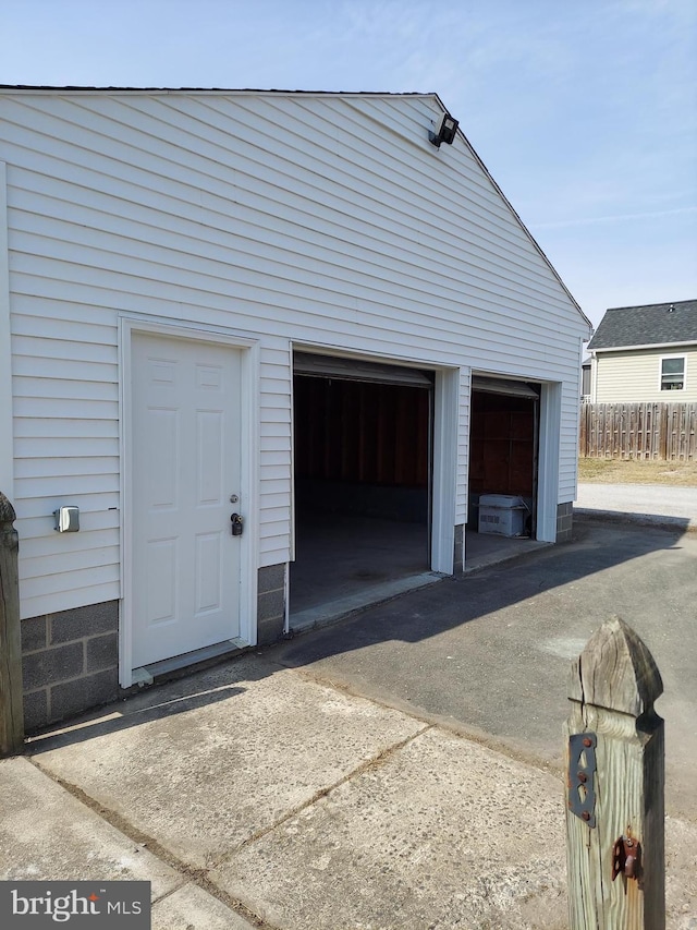 garage with fence and concrete driveway