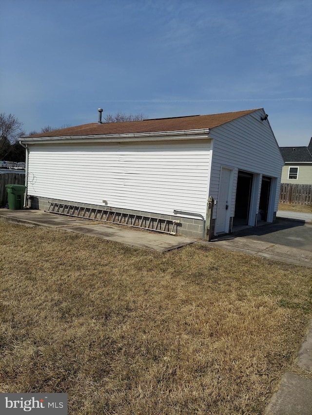 exterior space with a garage, an outbuilding, a yard, and fence