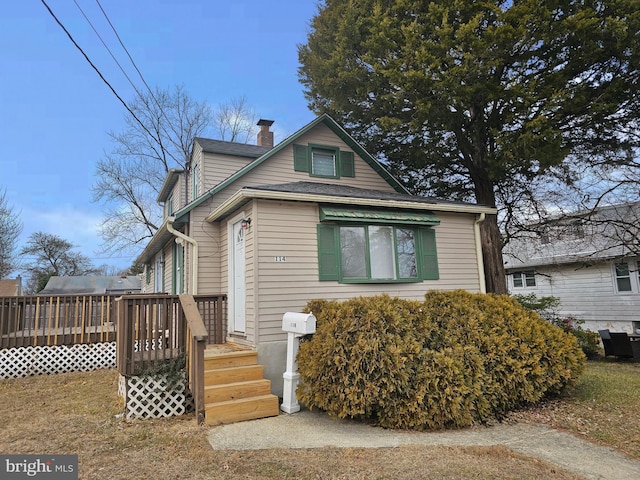 bungalow-style house with a chimney and a wooden deck