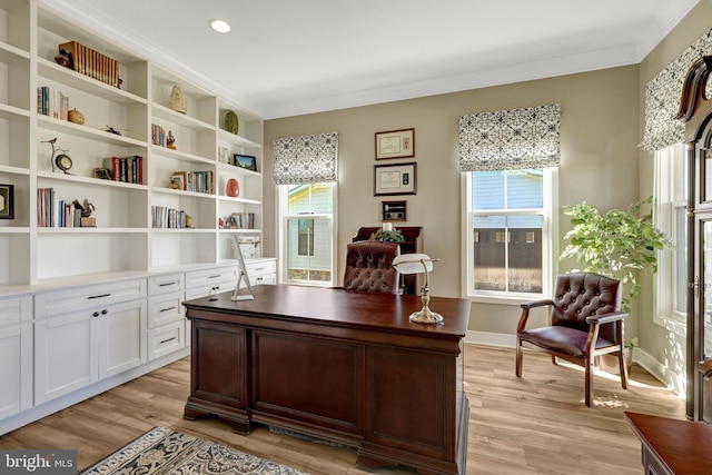 home office with a healthy amount of sunlight, ornamental molding, and light wood-type flooring