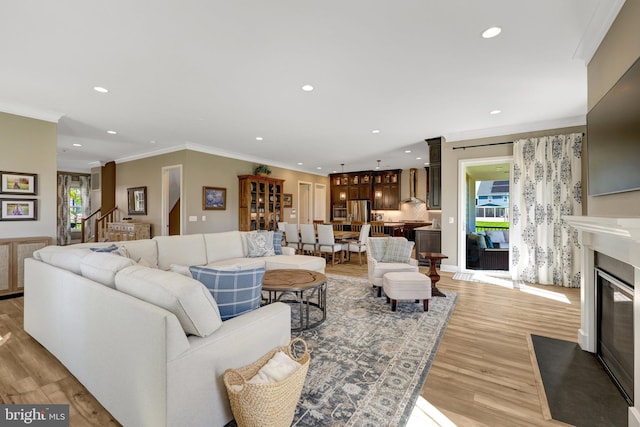 living area featuring recessed lighting, ornamental molding, and light wood-style floors