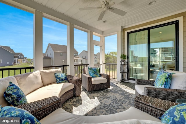 sunroom featuring a residential view, outdoor lounge area, and a ceiling fan