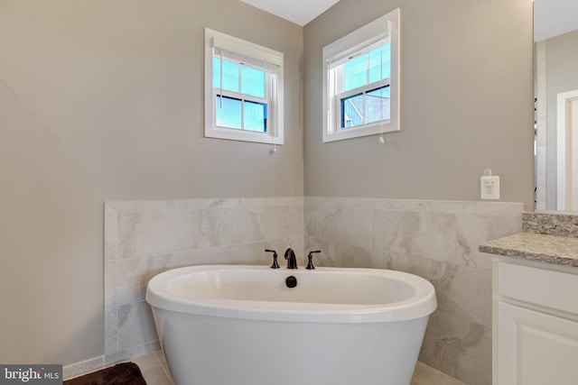 full bathroom featuring vanity, tile patterned floors, tile walls, and a soaking tub