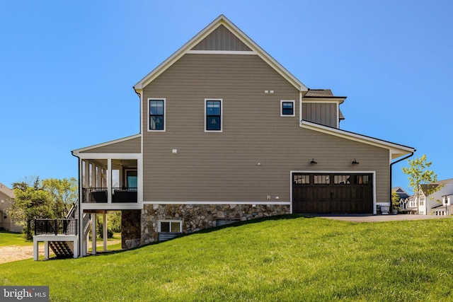 view of side of property with a yard, an attached garage, stairs, and a sunroom