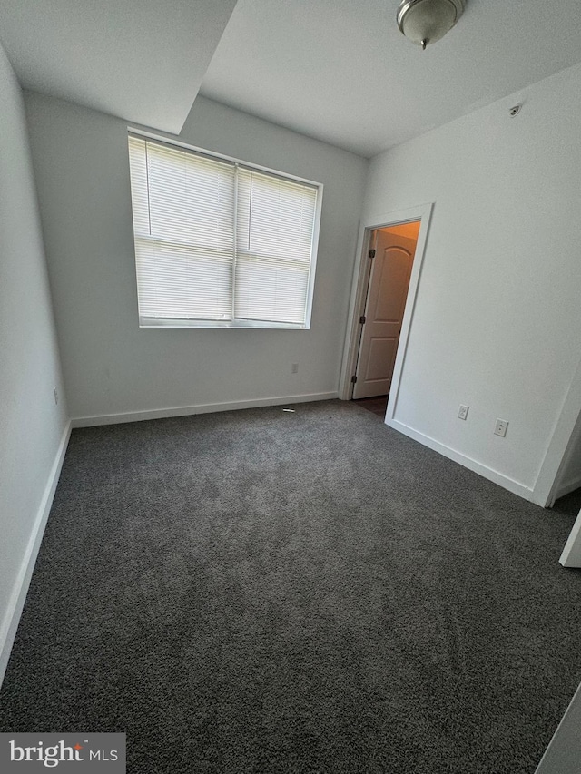 unfurnished bedroom featuring dark carpet and baseboards