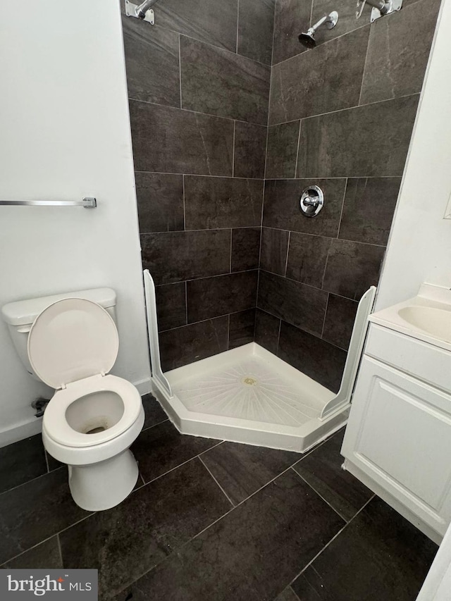 bathroom with toilet, a shower stall, baseboards, and tile patterned flooring