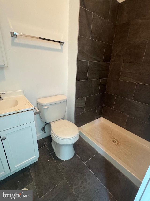 full bath with toilet, vanity, baseboards, tile patterned floors, and a stall shower