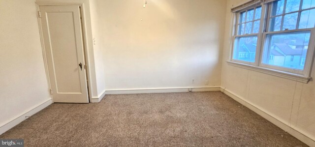 spare room featuring carpet flooring and baseboards