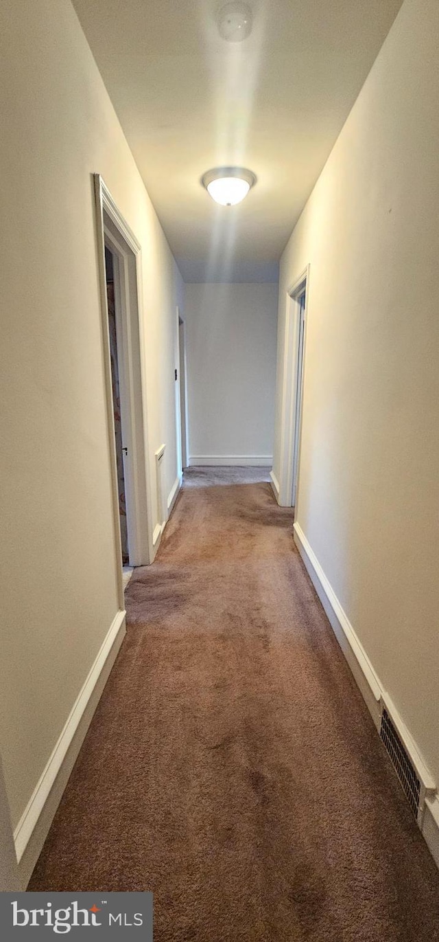 hall featuring visible vents, baseboards, and carpet