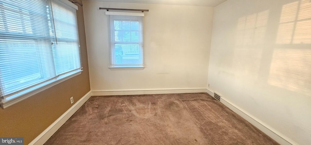 empty room featuring visible vents, baseboards, and carpet