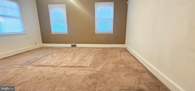 spare room with a wealth of natural light, visible vents, baseboards, and carpet flooring