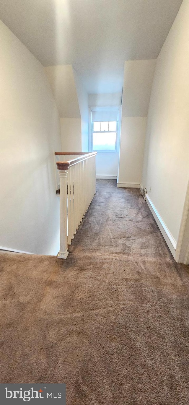 hall with an upstairs landing, baseboards, carpet, and vaulted ceiling